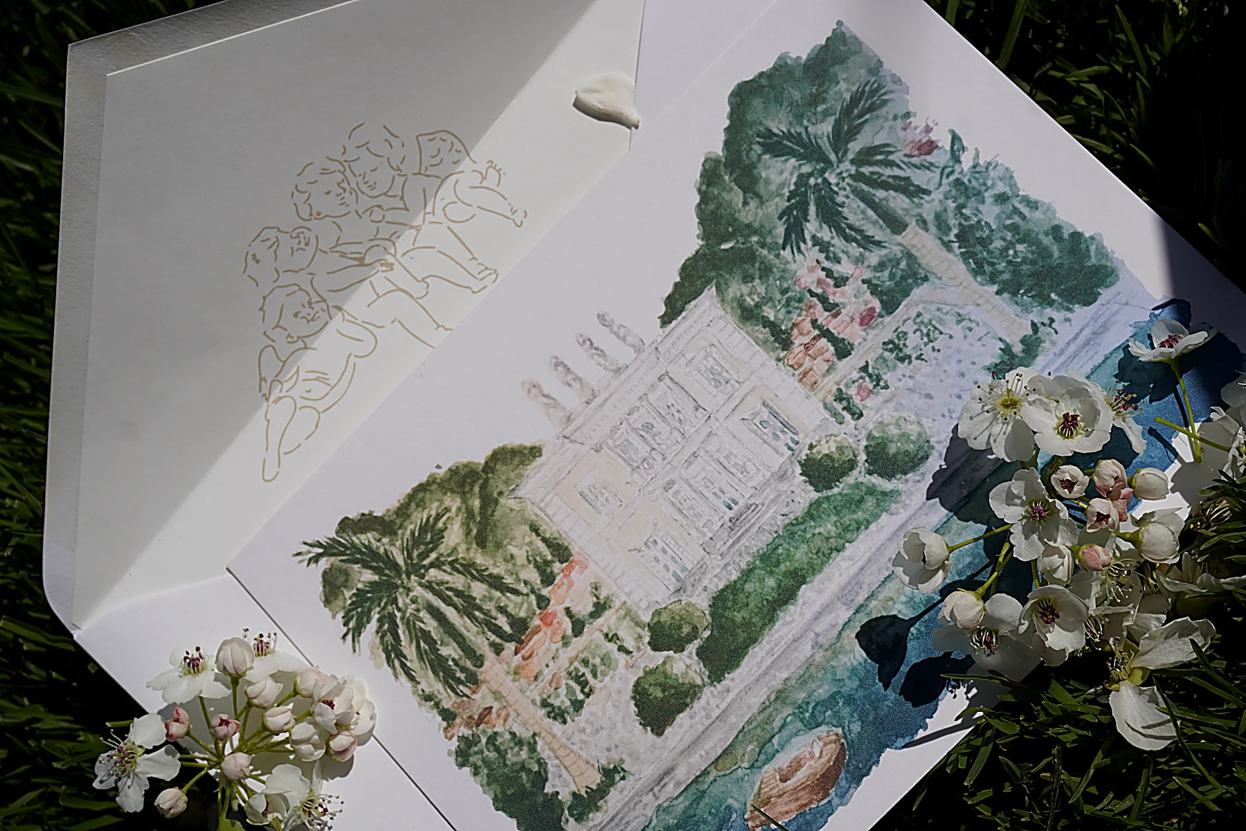 Printed wedding invitation with hand-painted venue illustration and gold cherub envelope liner