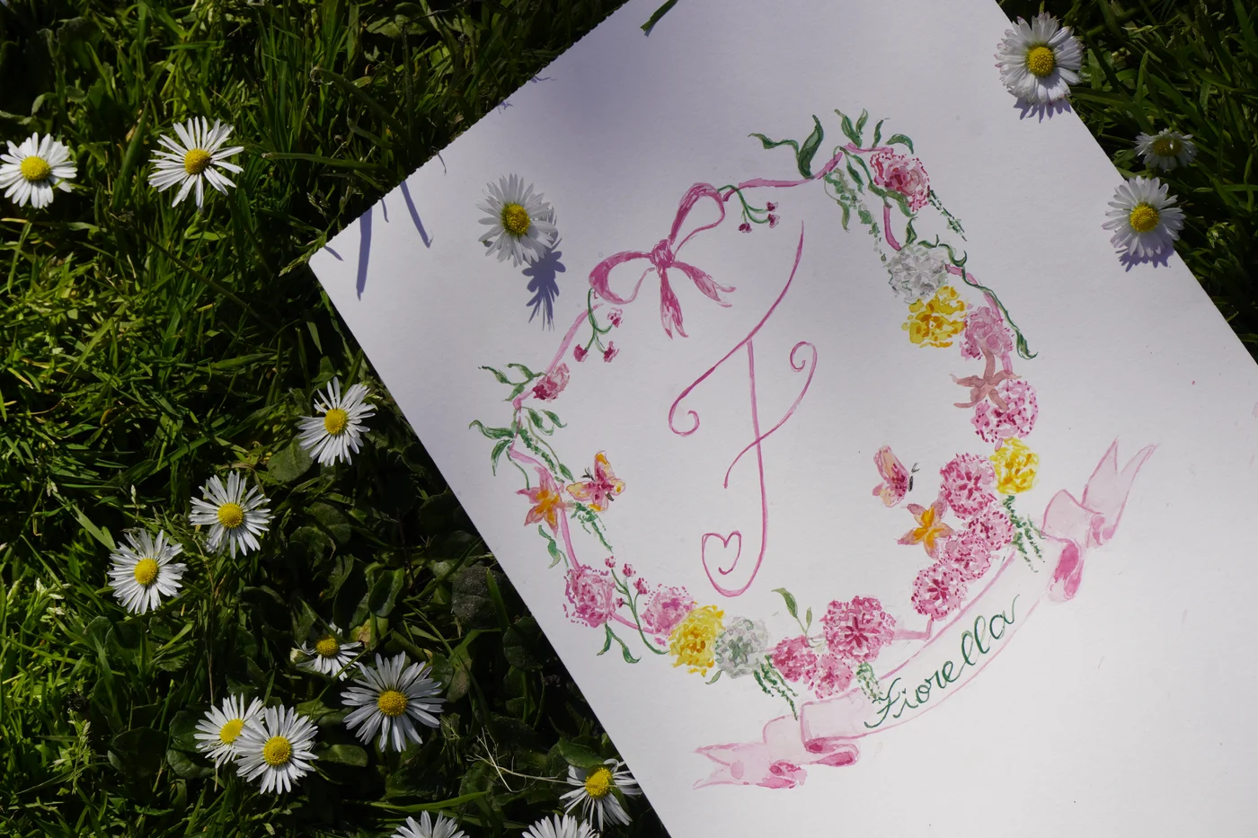 Printed monogram card with hand-painted wildflower wreath, photographed in the garden